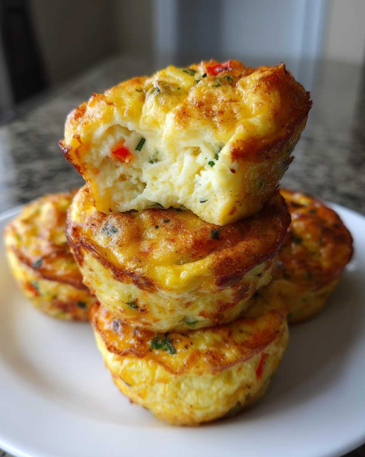 A stack of three golden-brown cottage cheese egg cups, one cut open to show the fluffy interior.