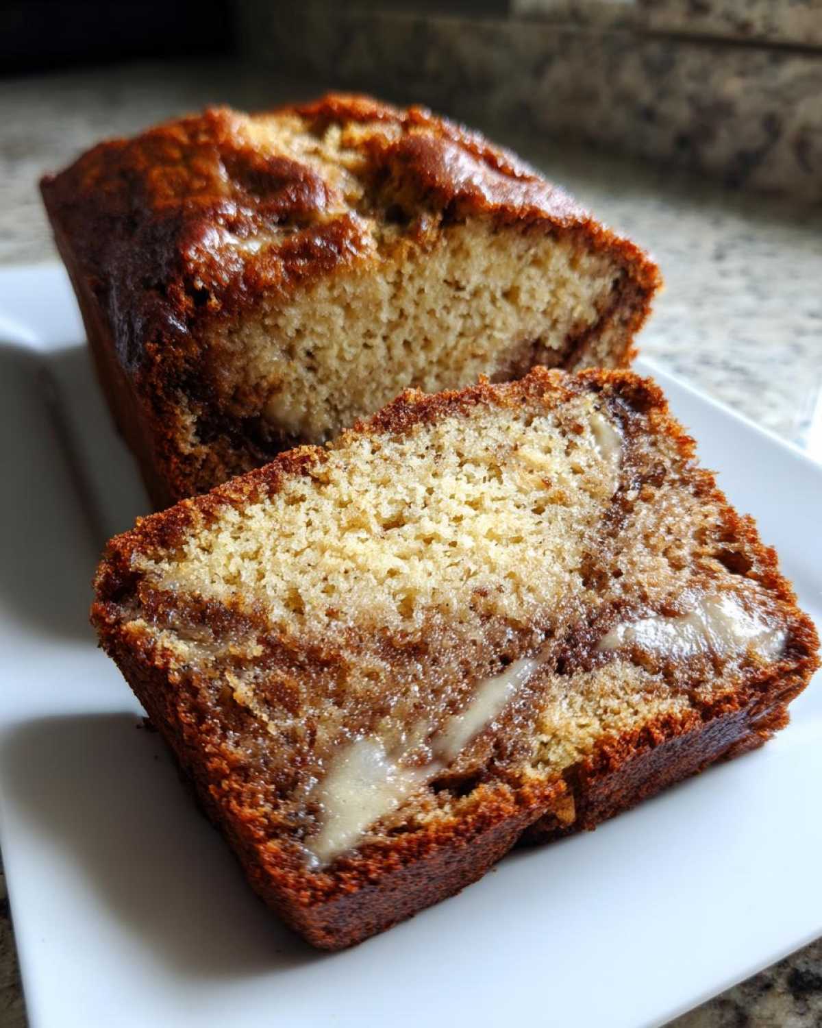 Close-up of a slice of cream cheese banana bread showing a rich, moist crumb and a visible swirl of cream cheese filling.