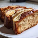 Two thick slices of moist cream cheese banana bread showing a caramelized banana topping.