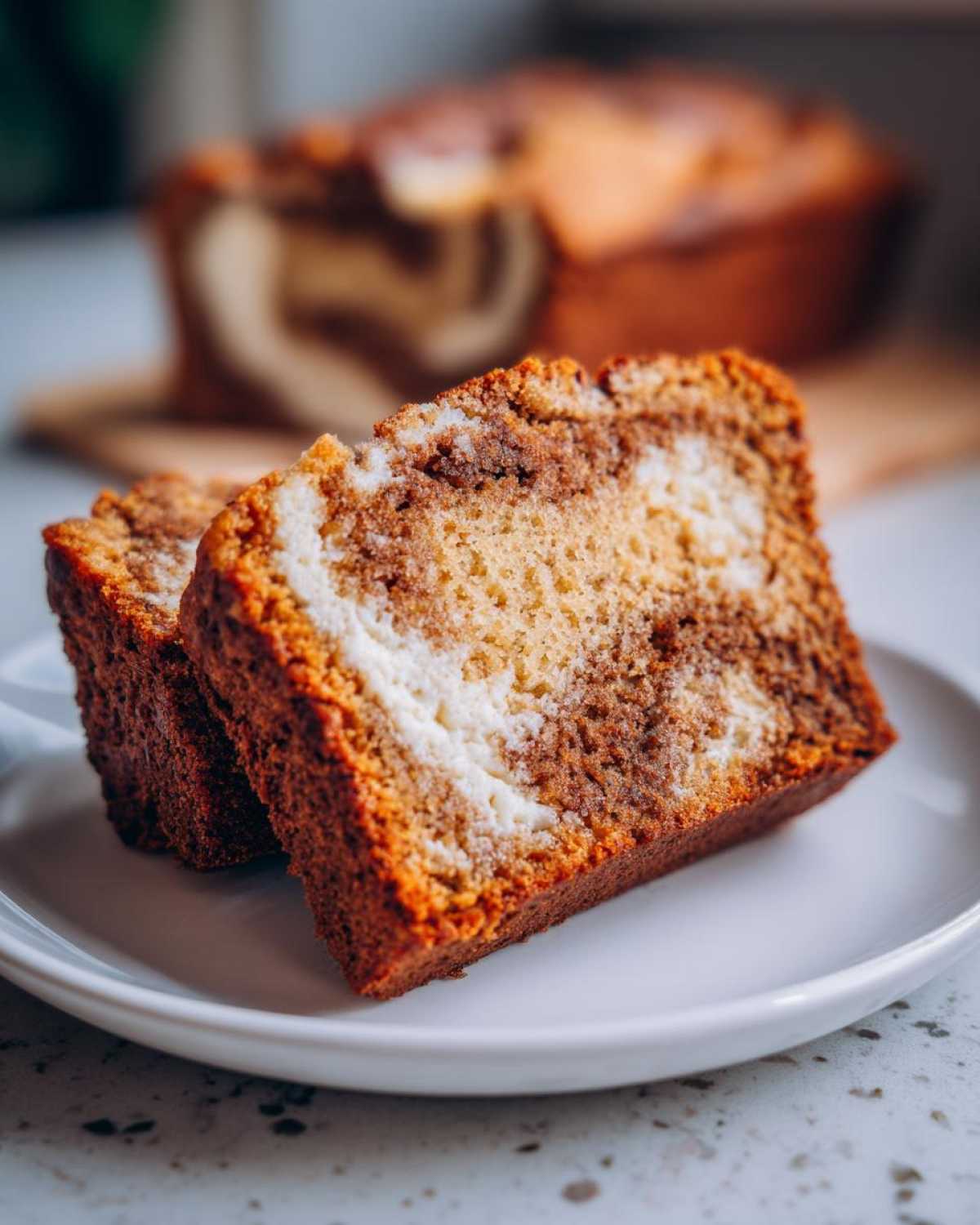 Two thick slices of cream cheese banana bread showing a beautiful swirl of cinnamon and cream cheese filling.