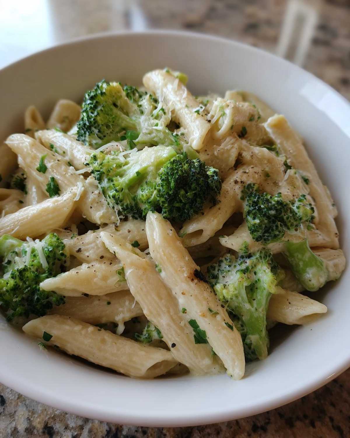 Close-up of creamy broccoli pasta made with penne, bright green broccoli florets, and grated cheese.