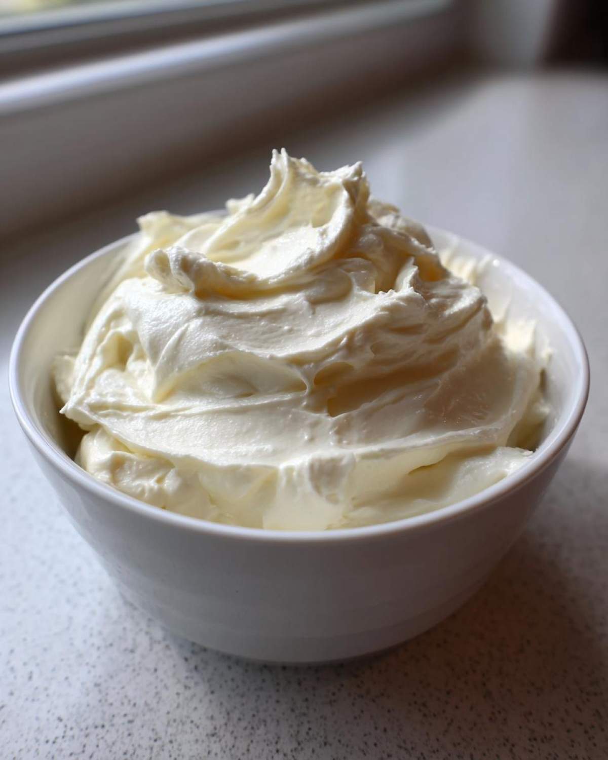 A close-up of thick, whipped, creamy fruit dip served in a small white bowl.