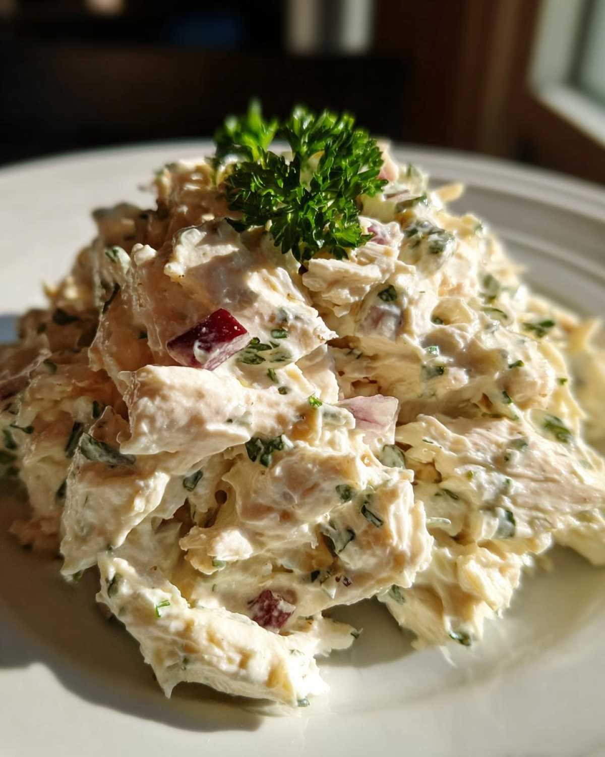 Close-up of creamy greek yogurt chicken salad piled high and garnished with fresh parsley.