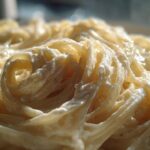 Extreme close-up of fettuccine pasta coated in rich, creamy Olive Garden Alfredo sauce.