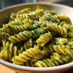 Close-up of creamy pesto pasta made with fusilli, topped with grated cheese.