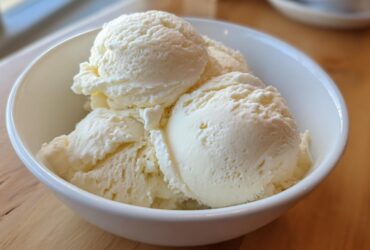 Close-up of several scoops of creamy vanilla protein ice cream served in a white bowl.