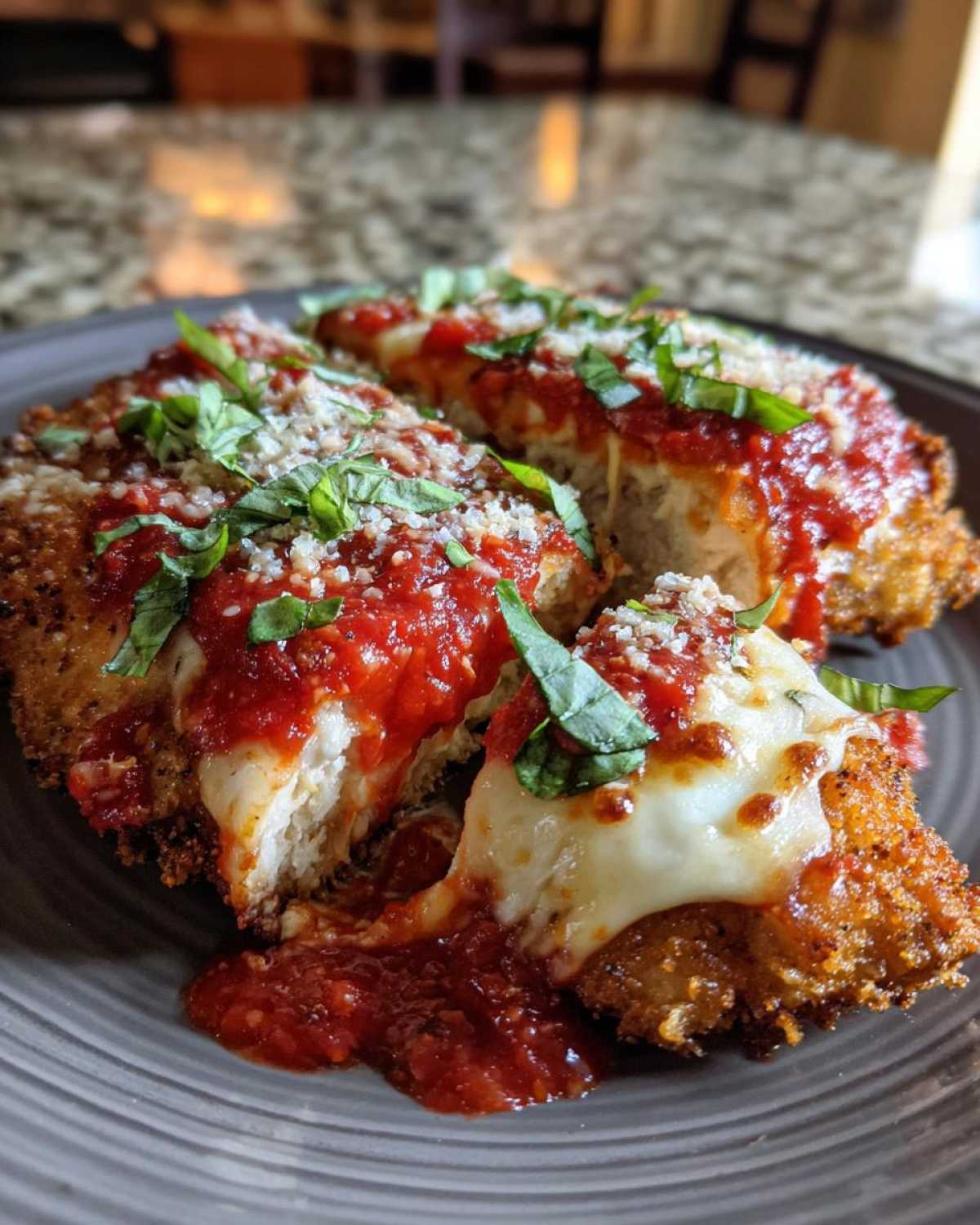 Close-up of sliced Easy chicken Parmesan topped with marinara sauce, melted mozzarella, and fresh basil.