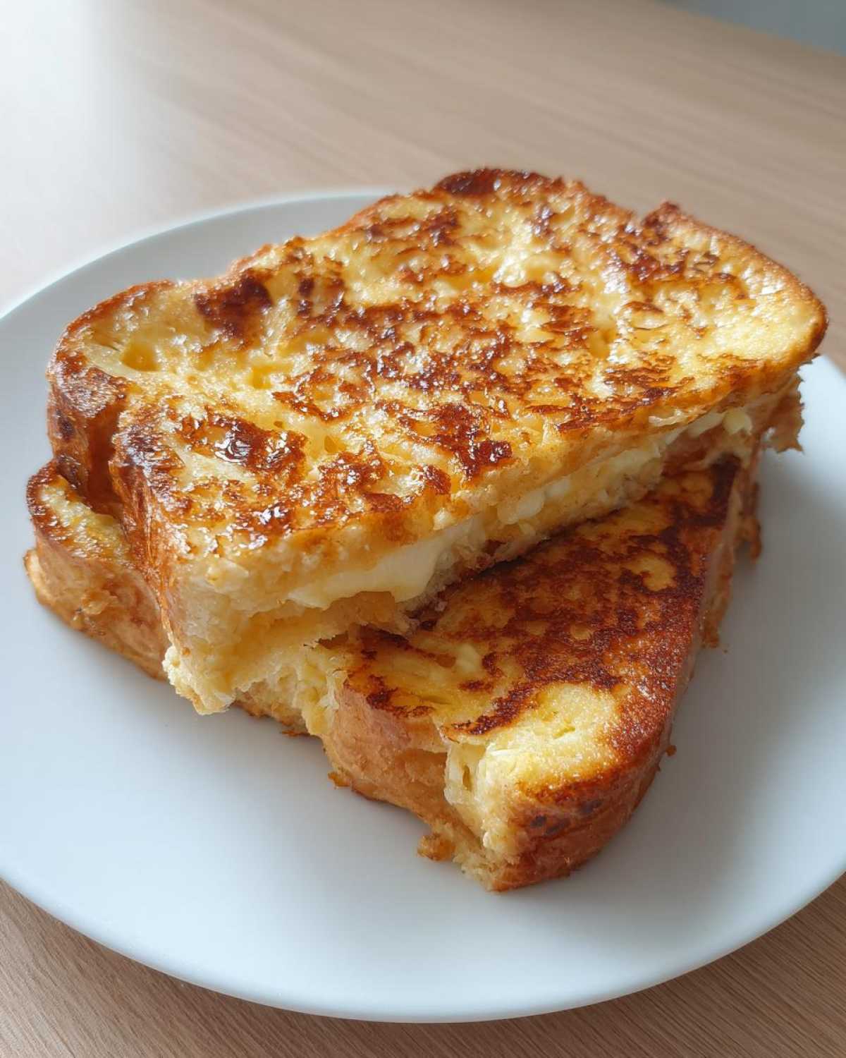 Two golden brown slices of easy french toast stacked on a white plate, showing a fluffy interior.