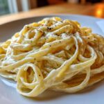 Close-up of fettuccine pasta coated in rich homemade alfredo sauce and topped with black pepper.