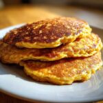 A stack of three golden-brown, fluffy banana pancakes resting on a light gray plate.