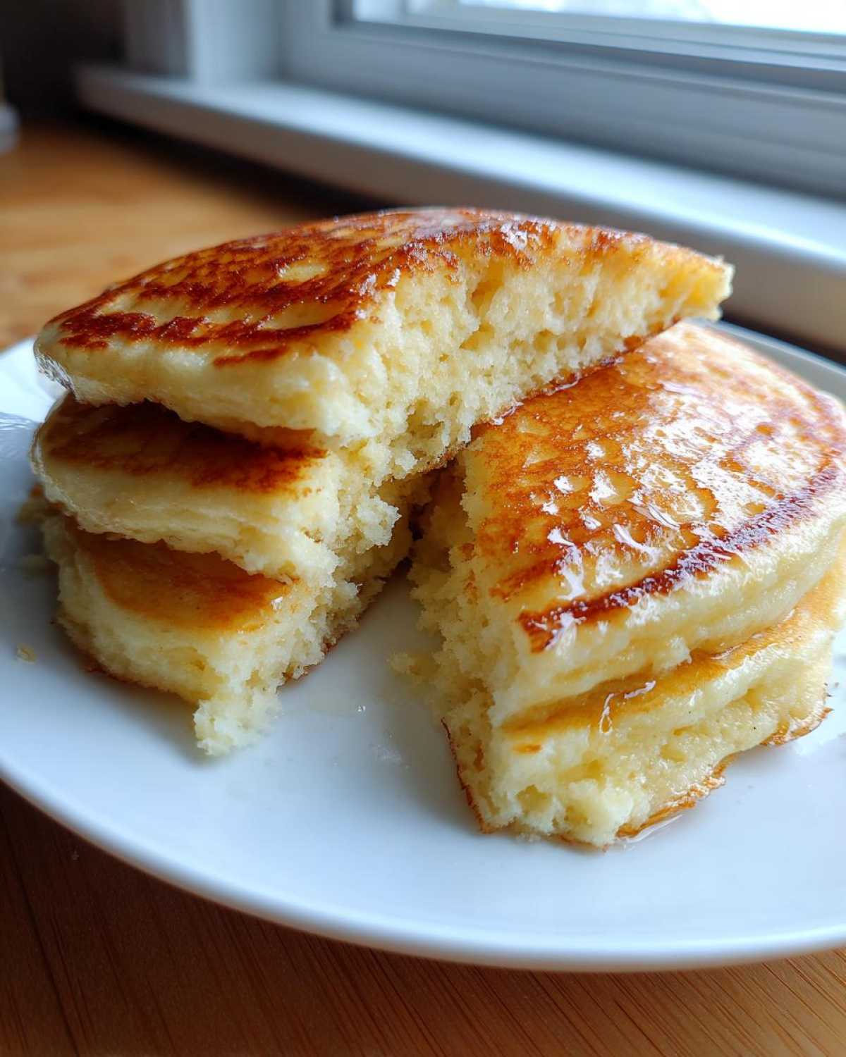 Close-up of fluffy coconut flour pancakes stacked and cut open, showing the light texture and syrup.