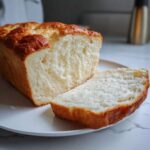 Close-up of a freshly baked loaf of condensed milk bread, showing its soft, white interior and golden crust.