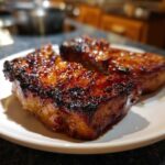 Close-up of three caramelized, glazed pieces of pork steak recipe served on a white plate.