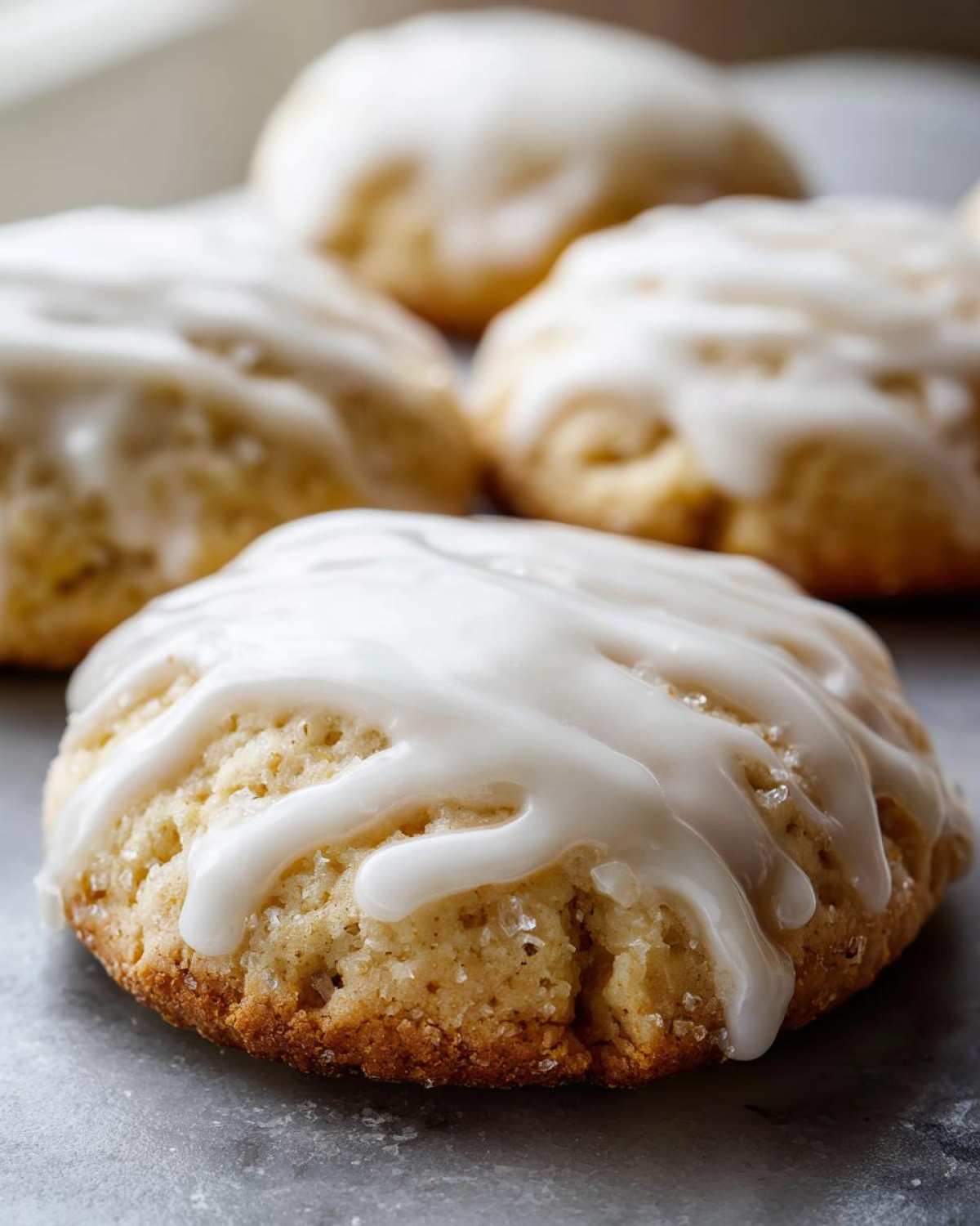 Close-up of a soft, glazed ricotta cookie with coarse sugar crystals visible on the bottom edge.