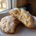 A soft, glazed ricotta cookie cut in half, showing its fluffy interior texture.