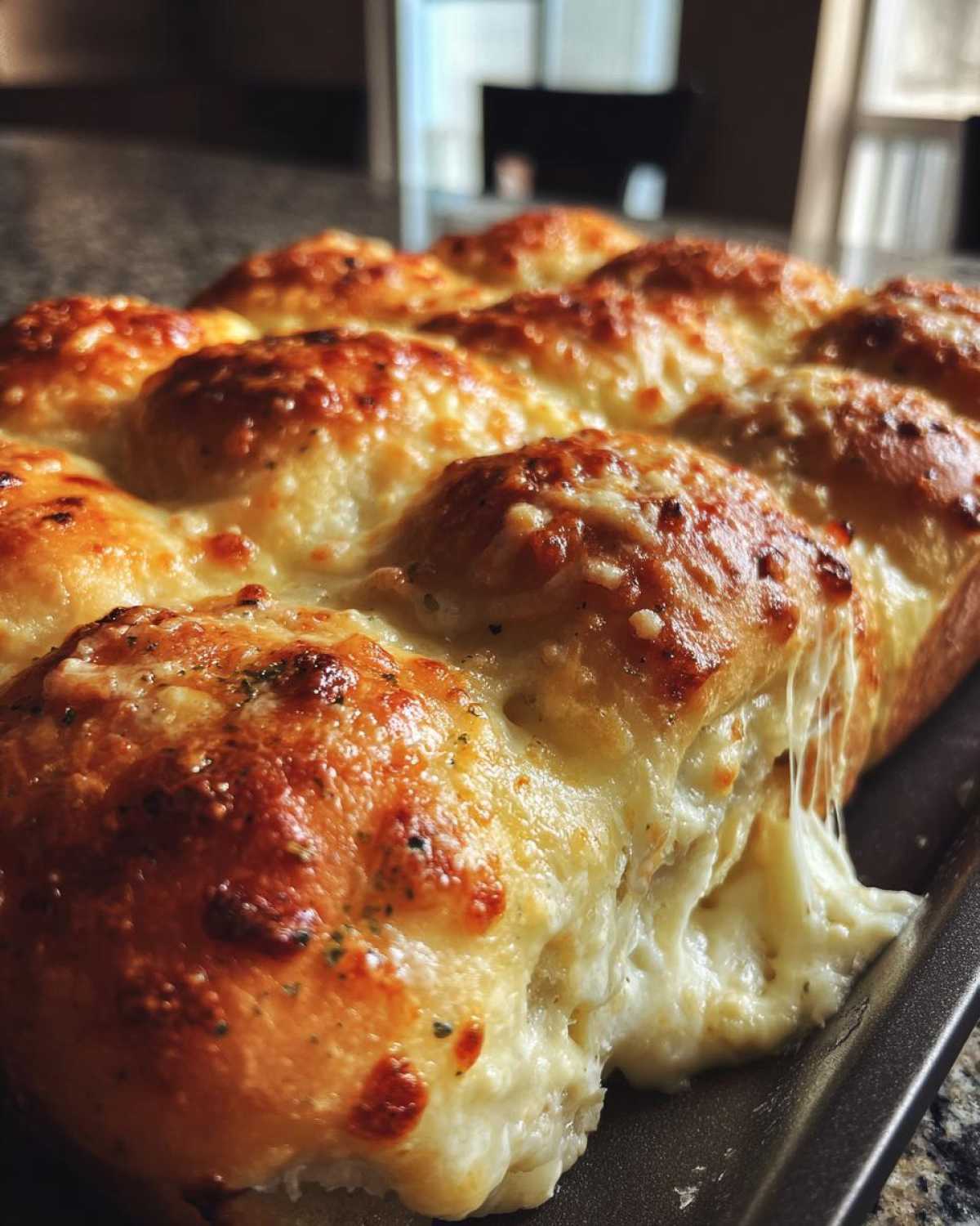 Close-up of freshly baked pizza sliders with melted, browned cheese and a dramatic cheese pull.