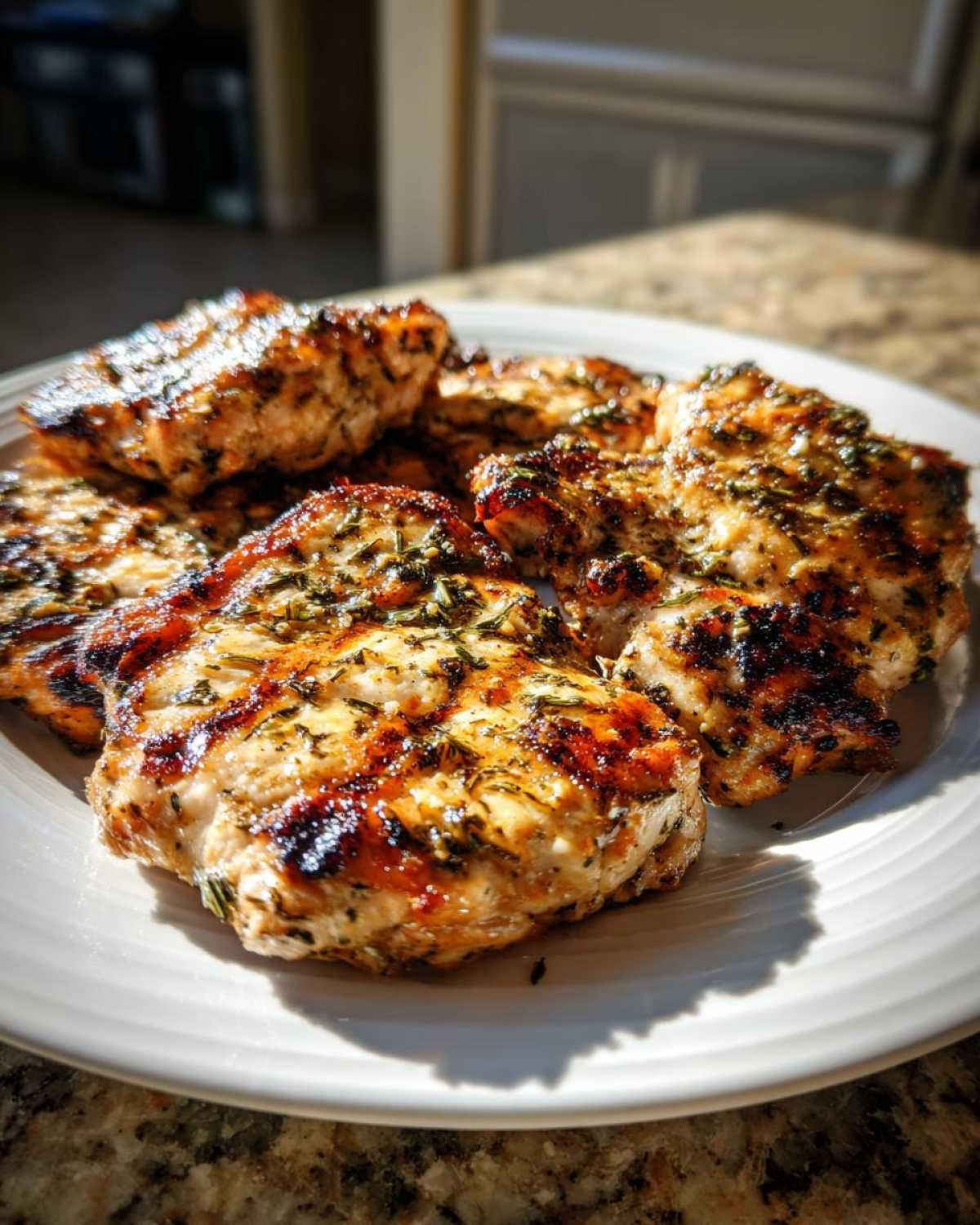 Close-up of grilled chicken pieces seasoned with herbs, showing grill marks, prepared using the best chicken marinade.