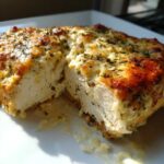 Cross-section of juicy caesar chicken breast topped with melted, browned cheese and herbs.