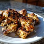 Close-up of golden brown, grilled chicken pieces seasoned with herbs, showing the results of a great chicken marinade.