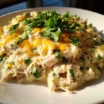A close-up serving of keto white chicken chili, topped with melted cheddar cheese and fresh cilantro.