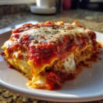 Close-up of a cheesy, saucy serving of lazy lasagna topped with herbs on a white plate.