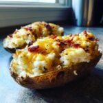 Close-up of a delicious twice baked potato stuffed with mashed potato, melted cheddar cheese, and bacon bits.