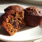 Close-up of moist bran muffins, one cut open showing raisins and a rich texture.