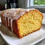 Close-up of a moist lemon pound cake loaf with thick white glaze dripping down the side.