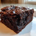 A close-up of a rich, dark, fudgy slice of sweet potato brownies on a white plate.