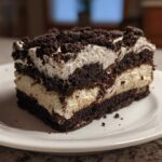 A decadent slice of no-bake dirt cake featuring alternating layers of dark chocolate cookie crumbs and creamy white filling.