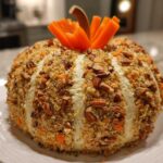 A beautifully shaped pumpkin cheese ball coated in pecans and breadcrumbs, ready for serving.