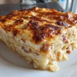 A thick, baked slice of creamy scalloped potatoes and ham showing layers and a golden-brown cheesy top.