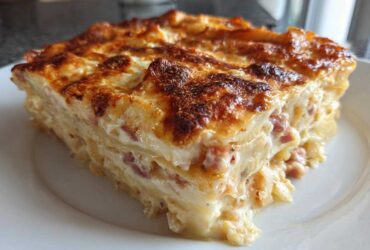 A thick, baked slice of creamy scalloped potatoes and ham showing layers and a golden-brown cheesy top.