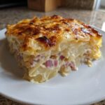 A close-up of a rich, creamy slice of scalloped potatoes and ham with a golden-brown, cheesy crust.