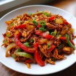 Close-up of shredded chicken mixed with colorful bell peppers and onions, perfect for crockpot chicken fajitas.