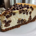 A perfect slice of rich chocolate chip cheesecake with a graham cracker crust, studded with chocolate chips.