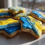Star-shaped sugar cookies decorated with bright yellow and blue sugar cookie icing that hardens, featuring white piped details.