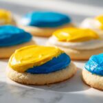 Close-up of sugar cookies topped with bright blue and yellow sugar cookie icing that hardens.