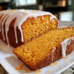 A slice cut from a loaf of moist sweet potato pound cake topped with a thick vanilla glaze.