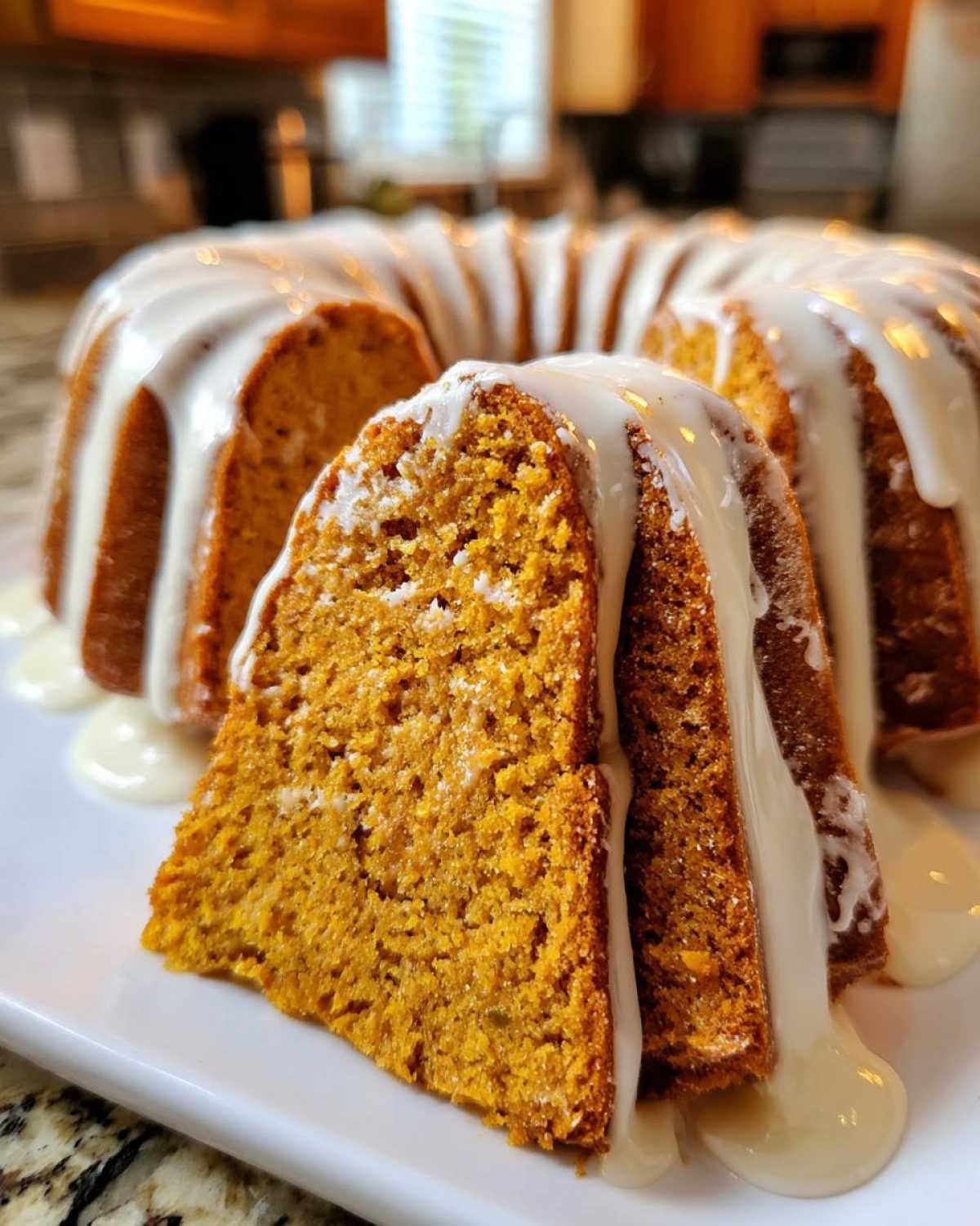 A slice cut from a moist sweet potato pound cake drizzled heavily with white vanilla glaze.