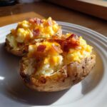 Two perfectly prepared twice baked potatoes stuffed with creamy filling, melted cheddar cheese, and crispy bacon bits.
