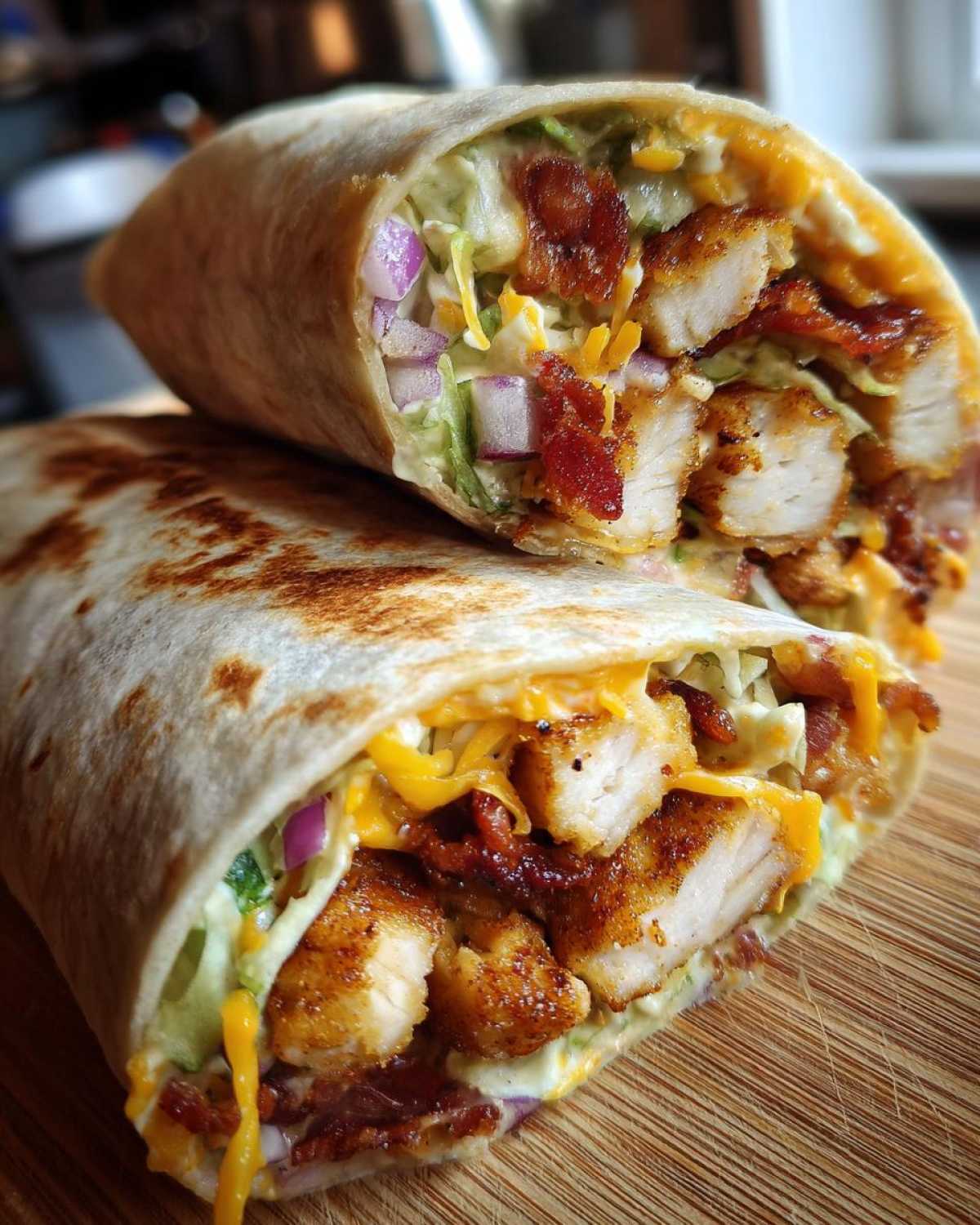 Close-up of a halved chicken bacon ranch wrap showing crispy chicken, bacon, cheese, and lettuce.