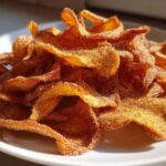 Close-up of a pile of crispy Air Fryer Cinnamon Sugar Apple Chips coated heavily in sugar and spice.