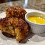 Two golden brown Air Fryer Crispy Crab Cakes served on a white plate with a side of bright yellow lemon aioli.