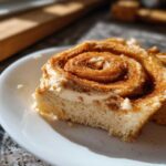 Close-up of a cinnamon roll slice topped with frosting and cinnamon, ready for Copycat Texas Roadhouse Cinnamon Honey Butter.