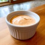 Close-up of creamy, orange-hued Copycat Outback Bloomin' Onion Sauce served in a small white ramekin.
