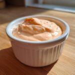 Close-up of creamy, orange-tinted Copycat Outback Bloomin' Onion Sauce served in a white ramekin.