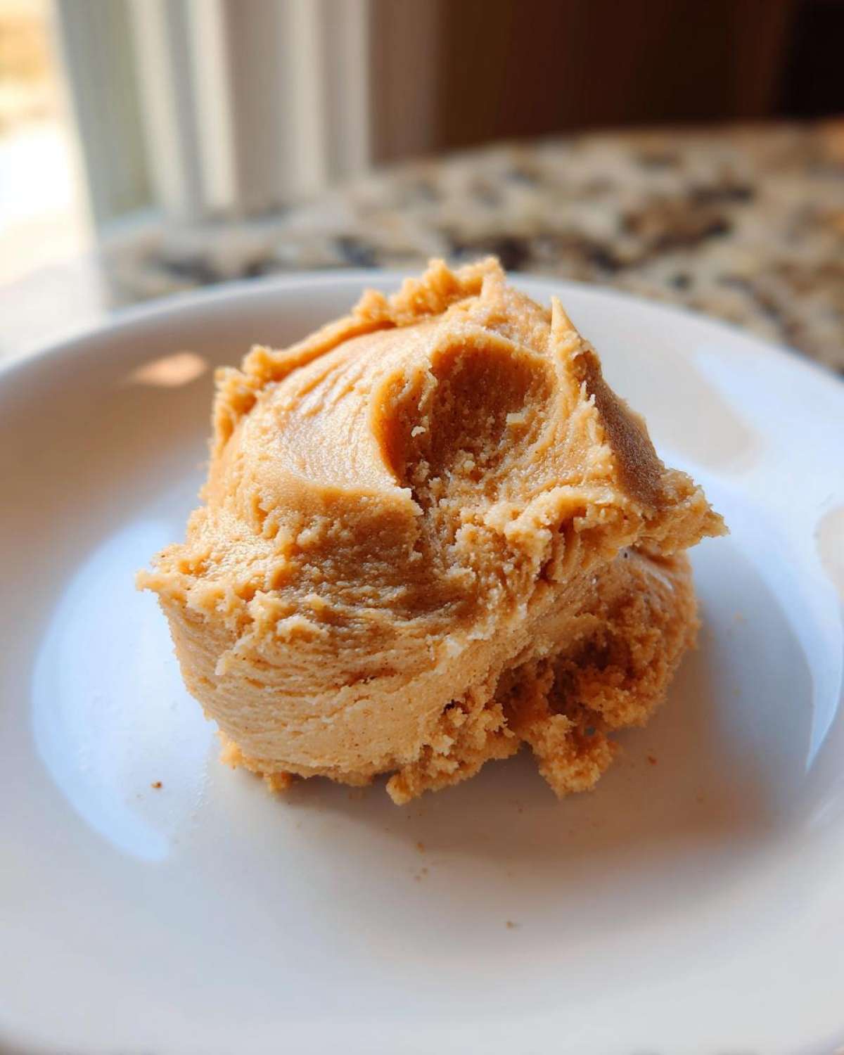 A close-up shot of a scoop of whipped Copycat Texas Roadhouse Cinnamon Honey Butter on a white plate.