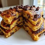 A stack of fluffy Gluten-Free Chocolate Chip Banana Pancakes cut open, drizzled with syrup and topped with chocolate chips.