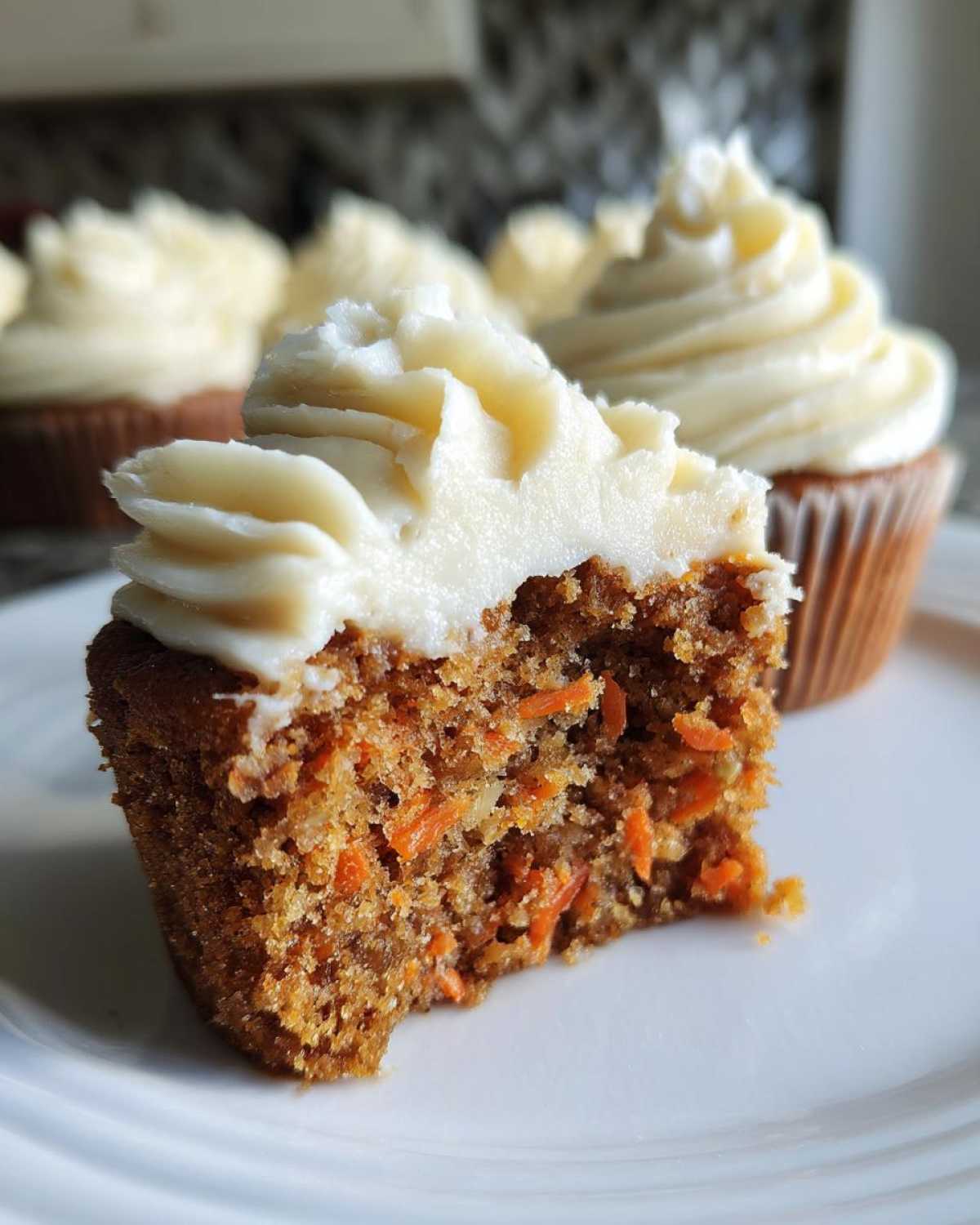 Close-up of a Gluten-Free Carrot Cake Cupcakes half, showing moist crumb and cream cheese frosting.
